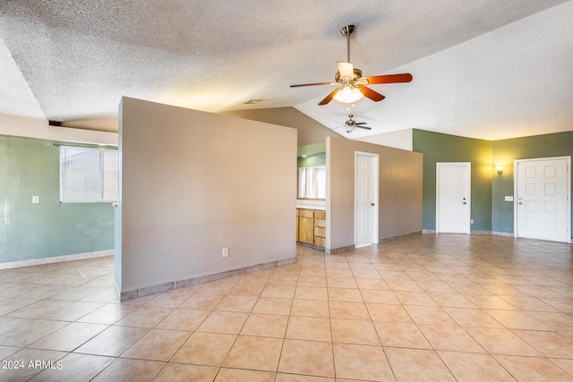 spare room with baseboards, ceiling fan, vaulted ceiling, light tile patterned flooring, and a textured ceiling