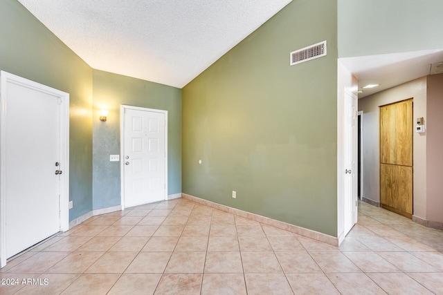 empty room featuring light tile patterned flooring, baseboards, visible vents, and a textured ceiling