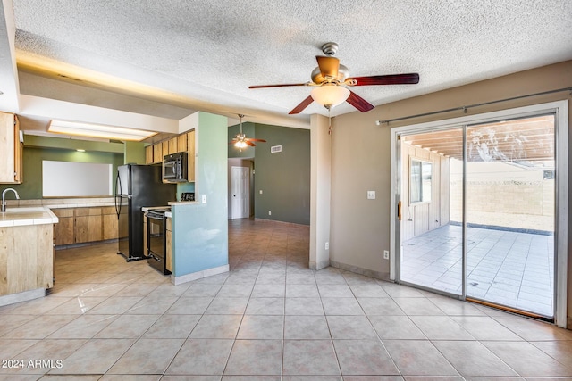 kitchen featuring black appliances, tile countertops, light tile patterned floors, and a sink