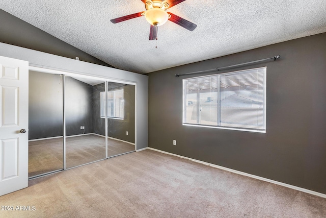 unfurnished bedroom with vaulted ceiling, multiple windows, a closet, and carpet floors