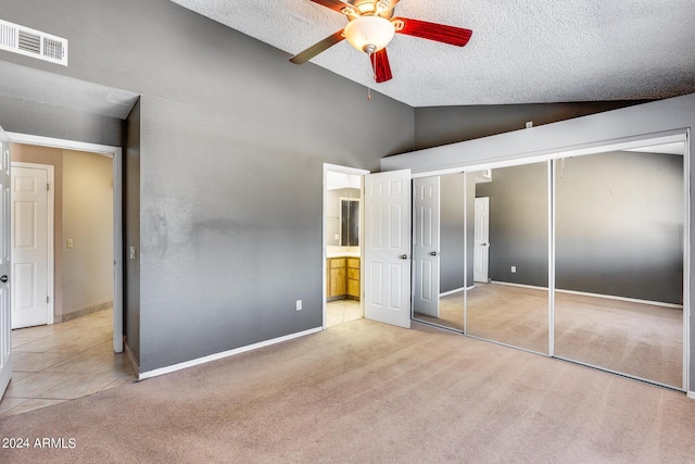 unfurnished bedroom featuring light carpet, visible vents, a textured ceiling, and lofted ceiling