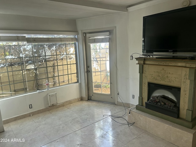 unfurnished living room featuring a healthy amount of sunlight, light tile patterned floors, and crown molding