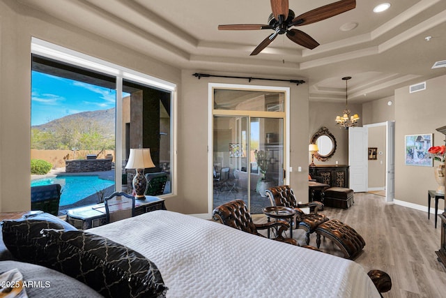 bedroom featuring a notable chandelier, wood finished floors, visible vents, baseboards, and a raised ceiling