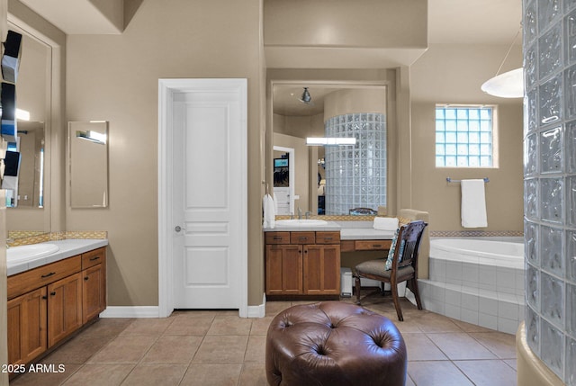 bathroom featuring a sink, tiled tub, two vanities, and tile patterned flooring