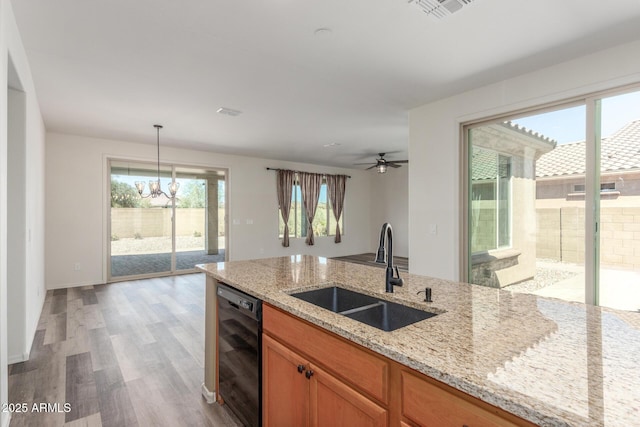 kitchen featuring visible vents, dishwasher, light wood-style flooring, light stone counters, and a sink