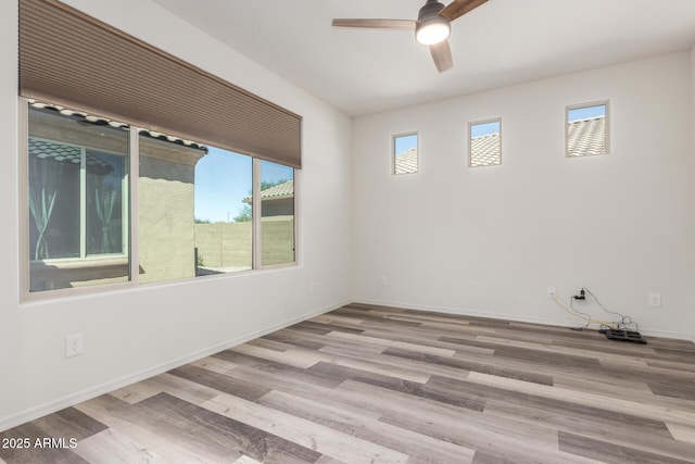 spare room featuring a ceiling fan, baseboards, and wood finished floors