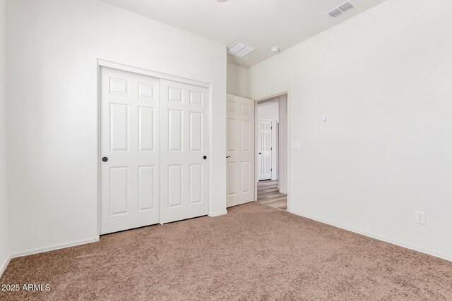 unfurnished bedroom featuring baseboards, a closet, visible vents, and carpet flooring