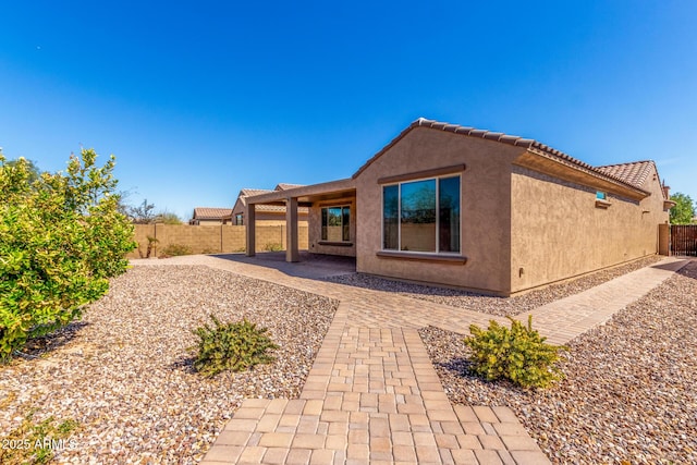 back of property with a patio area, a fenced backyard, a tile roof, and stucco siding