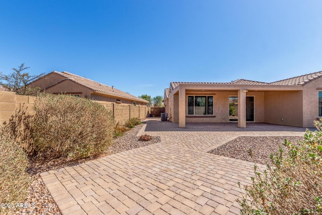 rear view of house featuring a tile roof, a patio, stucco siding, cooling unit, and a fenced backyard