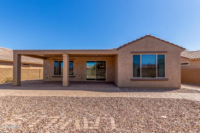 rear view of house featuring a patio, fence, a tiled roof, and stucco siding