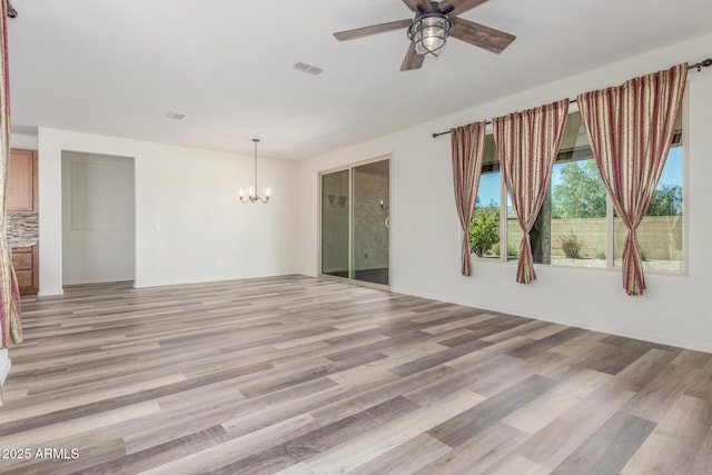 spare room with light wood-style flooring, visible vents, and ceiling fan with notable chandelier