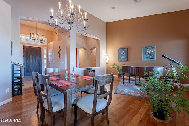 dining room featuring a towering ceiling, hardwood / wood-style flooring, and a notable chandelier