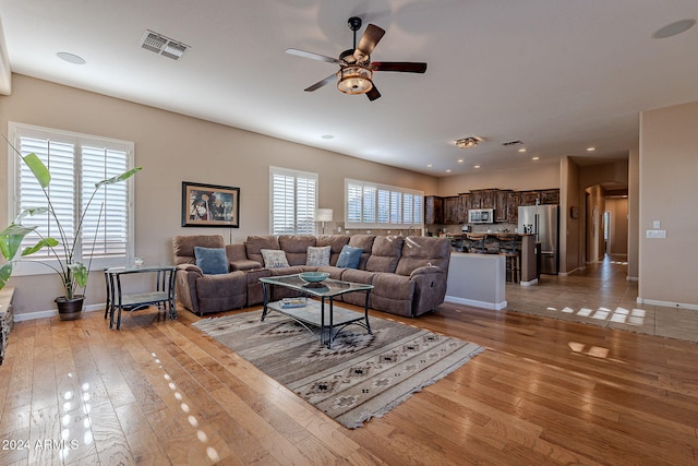 living room featuring ceiling fan, light hardwood / wood-style floors, and a healthy amount of sunlight