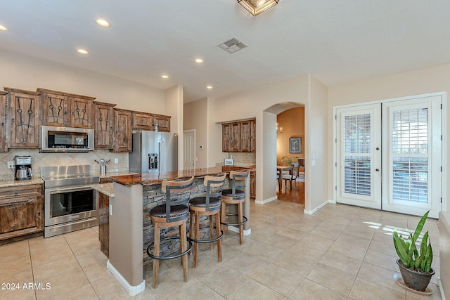 kitchen with a kitchen breakfast bar, stainless steel appliances, light stone counters, and a center island