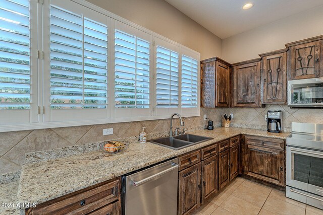 kitchen with a wealth of natural light, stainless steel appliances, sink, and light stone countertops