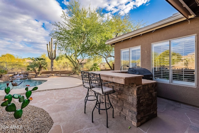 view of patio / terrace with a fenced in pool, exterior bar, and grilling area