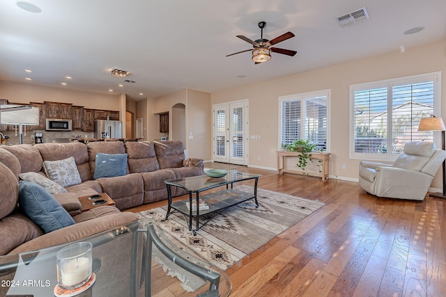 living room with ceiling fan, plenty of natural light, light wood-type flooring, and french doors