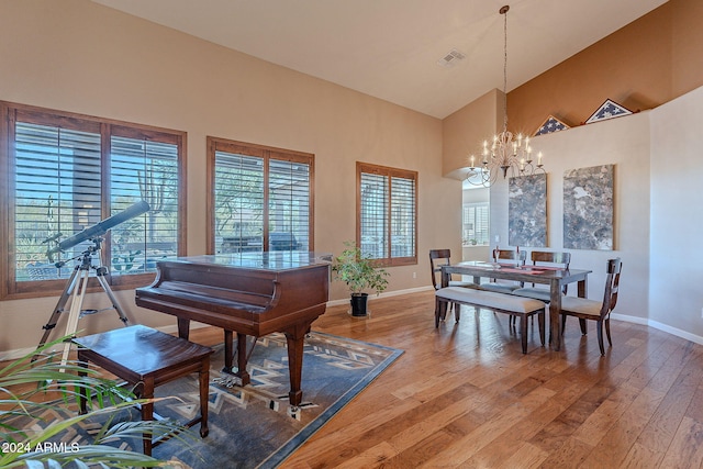 miscellaneous room with high vaulted ceiling, an inviting chandelier, and hardwood / wood-style flooring