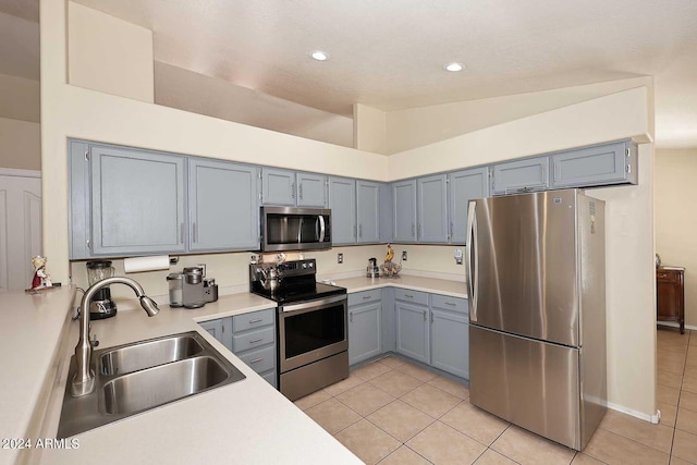 kitchen with vaulted ceiling, light tile patterned floors, stainless steel appliances, and sink