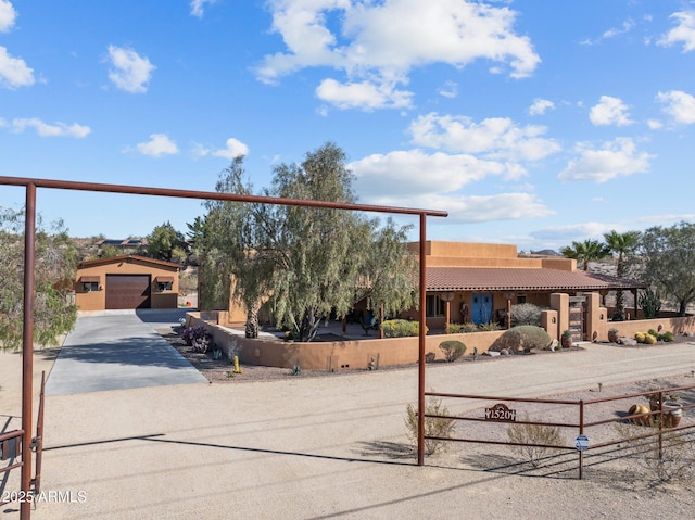 pueblo revival-style home with a fenced front yard, stucco siding, a tiled roof, and a garage