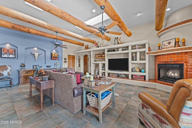 living room featuring beamed ceiling, ceiling fan, and a tile fireplace