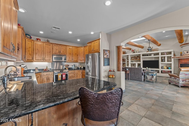 kitchen featuring visible vents, open floor plan, a peninsula, stainless steel appliances, and a sink