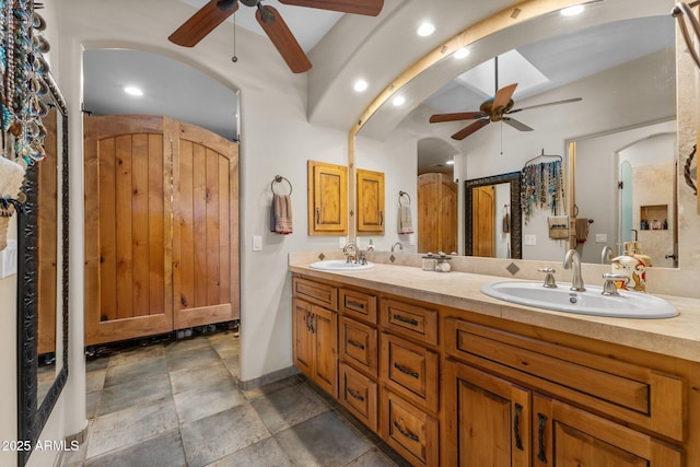 full bathroom with a sink, a ceiling fan, double vanity, and stone finish floor