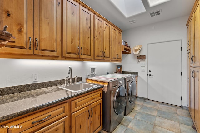 washroom with visible vents, washer and clothes dryer, stone finish floor, cabinet space, and a sink