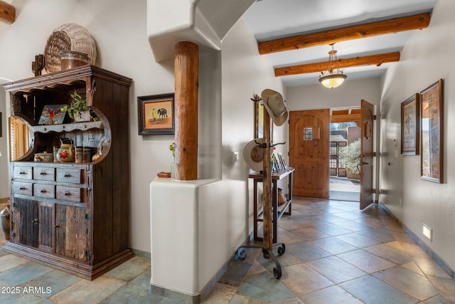 foyer entrance with beam ceiling, decorative columns, and baseboards