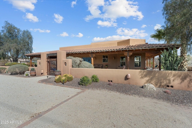 pueblo-style house featuring a gate, a fenced front yard, and stucco siding