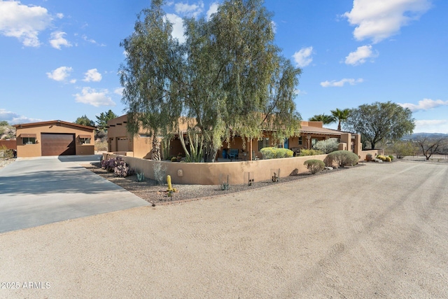 pueblo revival-style home with a fenced front yard, driveway, and stucco siding