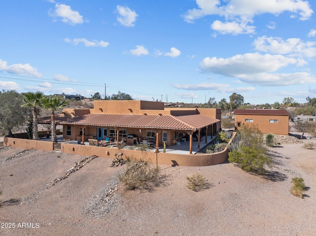 rear view of house with a tile roof, a patio area, driveway, and stucco siding