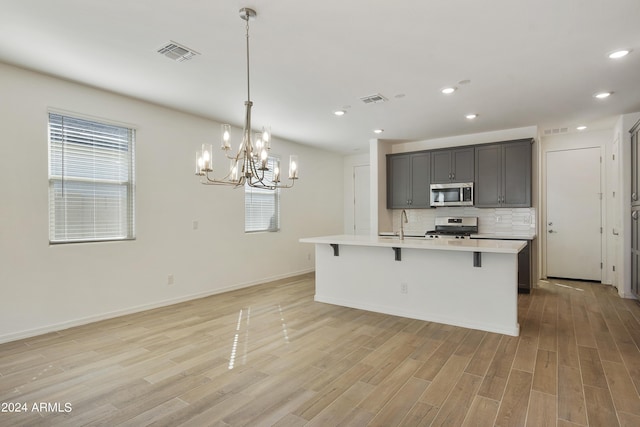 kitchen featuring tasteful backsplash, light countertops, visible vents, light wood-style flooring, and appliances with stainless steel finishes