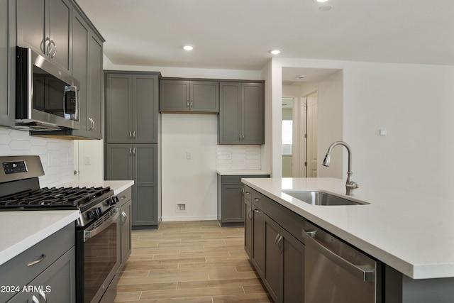 kitchen with wood finish floors, stainless steel appliances, recessed lighting, light countertops, and a sink