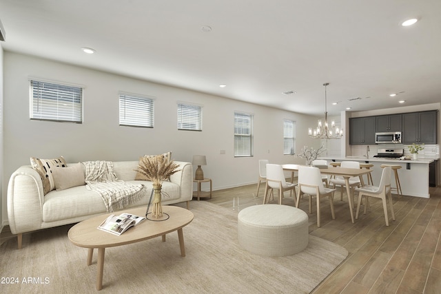 living area with recessed lighting, light wood-type flooring, a wealth of natural light, and a notable chandelier