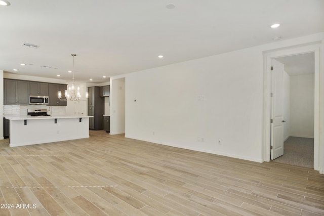 unfurnished living room featuring light wood-style floors, recessed lighting, visible vents, and an inviting chandelier