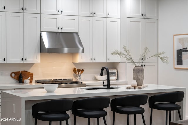 kitchen with a kitchen bar, white cabinetry, extractor fan, and sink