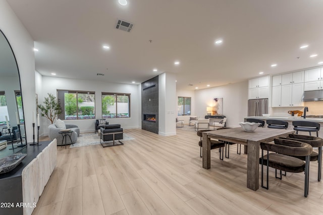 dining room featuring a tile fireplace and light wood-type flooring