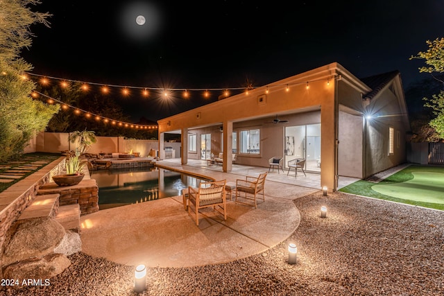 pool at night featuring ceiling fan and a patio