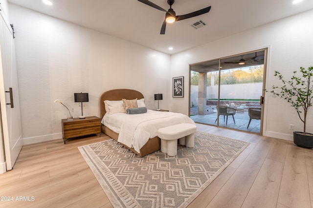 bedroom with hardwood / wood-style flooring, ceiling fan, a barn door, and access to outside