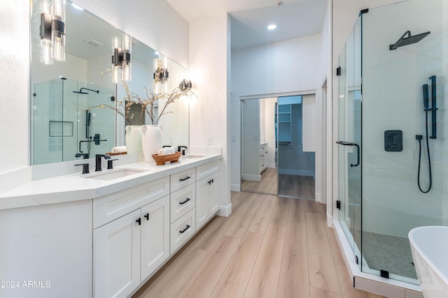 bathroom with plus walk in shower, hardwood / wood-style floors, and vanity