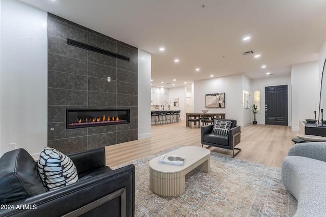 living room with a tile fireplace and light hardwood / wood-style floors