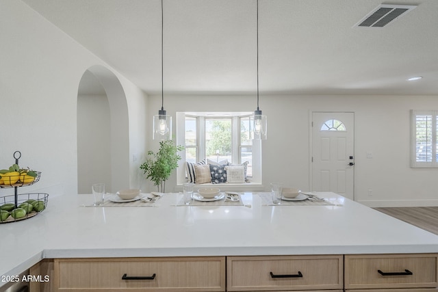 2337 E Contessa St, Mesa, AZ 85213 - kitchen featuring arched walkways, light countertops, light brown cabinetry, and hanging light fixtures