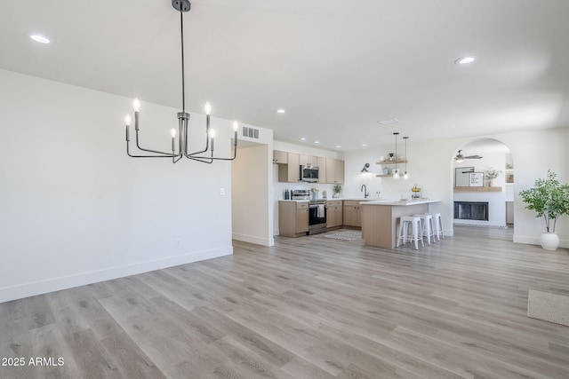 2337 E Contessa St, Mesa, AZ 85213 - unfurnished living room with a chandelier, recessed lighting, arched walkways, light wood-style floors, and a fireplace