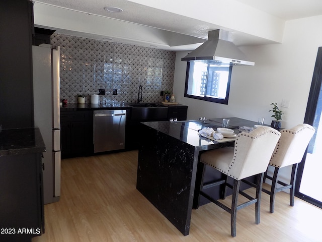 kitchen with appliances with stainless steel finishes, backsplash, light wood-type flooring, and island range hood