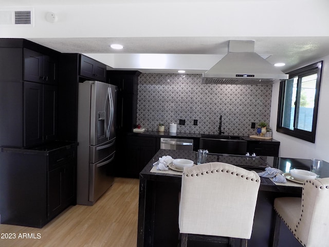 kitchen with appliances with stainless steel finishes, light hardwood / wood-style floors, sink, tasteful backsplash, and island exhaust hood