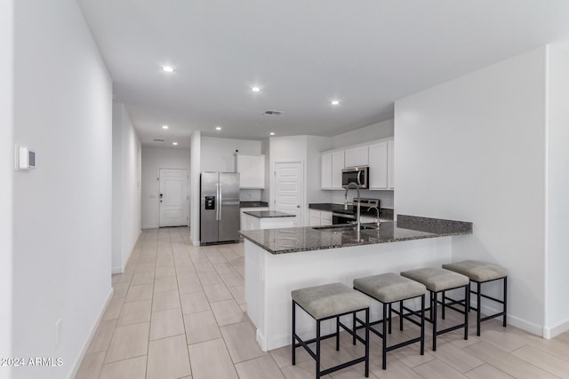 kitchen featuring a kitchen breakfast bar, kitchen peninsula, white cabinets, and stainless steel appliances