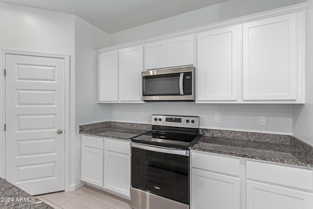 kitchen featuring dark stone countertops, white cabinetry, light tile patterned floors, and stainless steel appliances