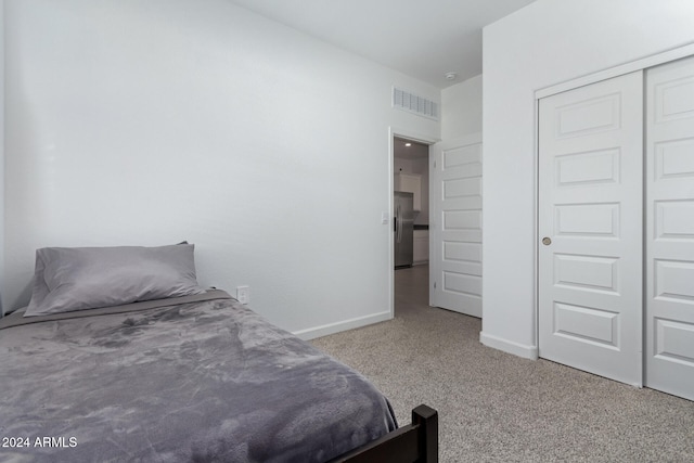 carpeted bedroom featuring stainless steel fridge and a closet