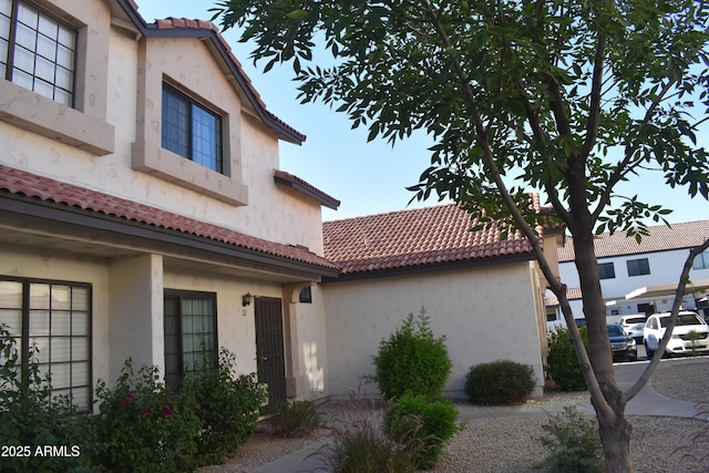 view of property exterior with a tile roof and stucco siding